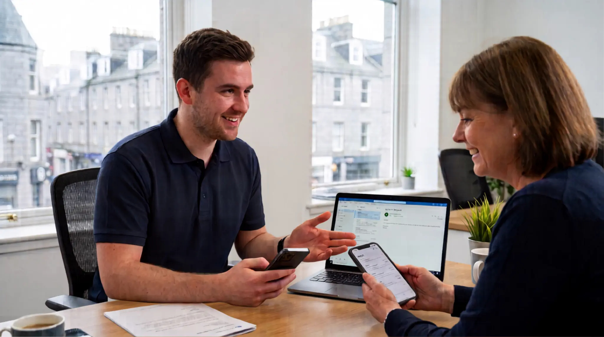 Engineer setting up business email on laptop and phones in an Aberdeen office